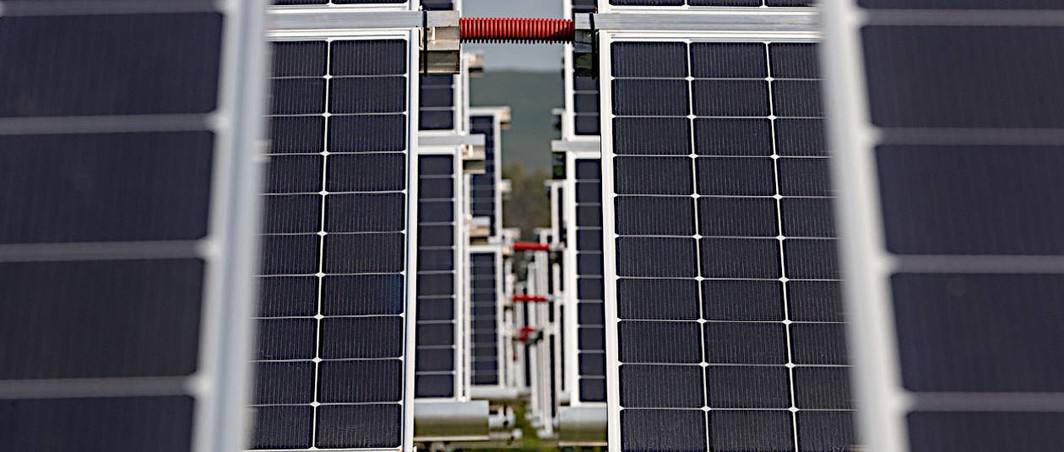 View through neighboring solar panel rows in a solar plant built by Hevel Solar