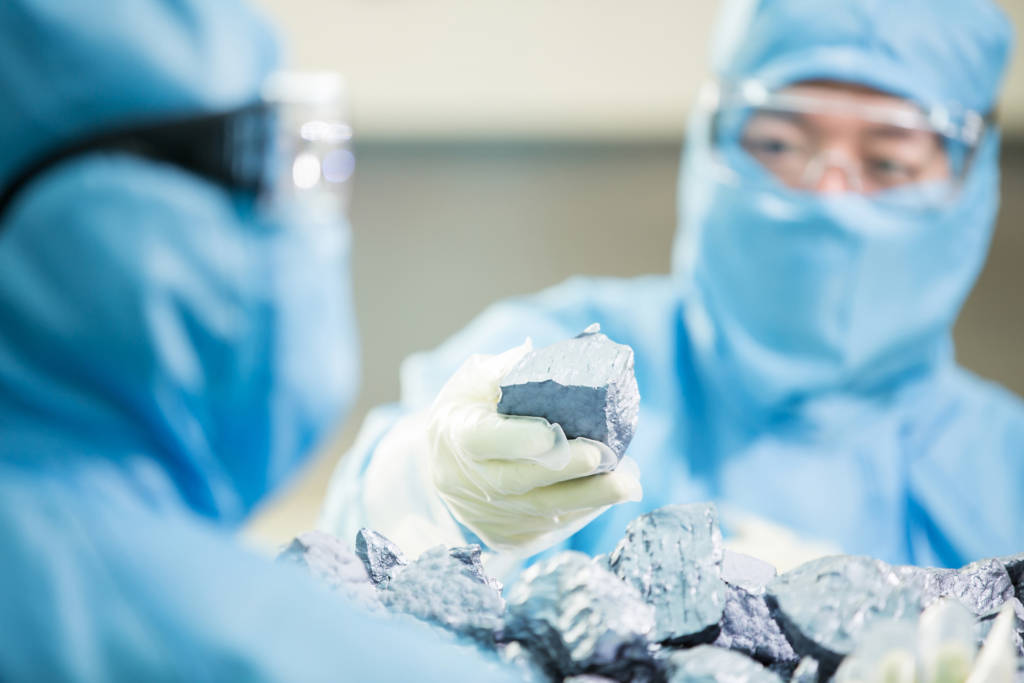 Two technicians of OCI Company in cleanroom suits, holding high-purity polysilicon chunks